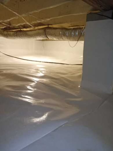 A clean, encapsulated crawl space with white plastic sheeting covering the floor and walls, and an insulated air duct running along the ceiling.